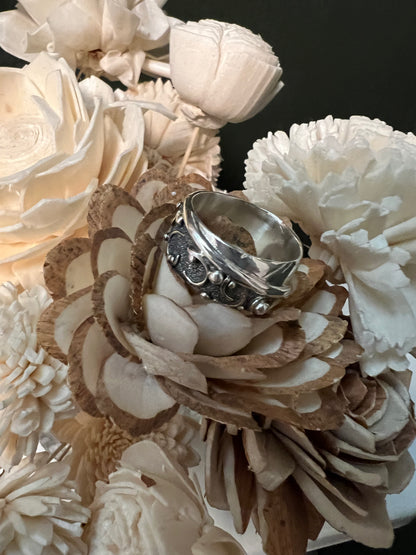Wide Feather Ring – front view of handcrafted sterling silver wide feather band ring worn on finger, black background