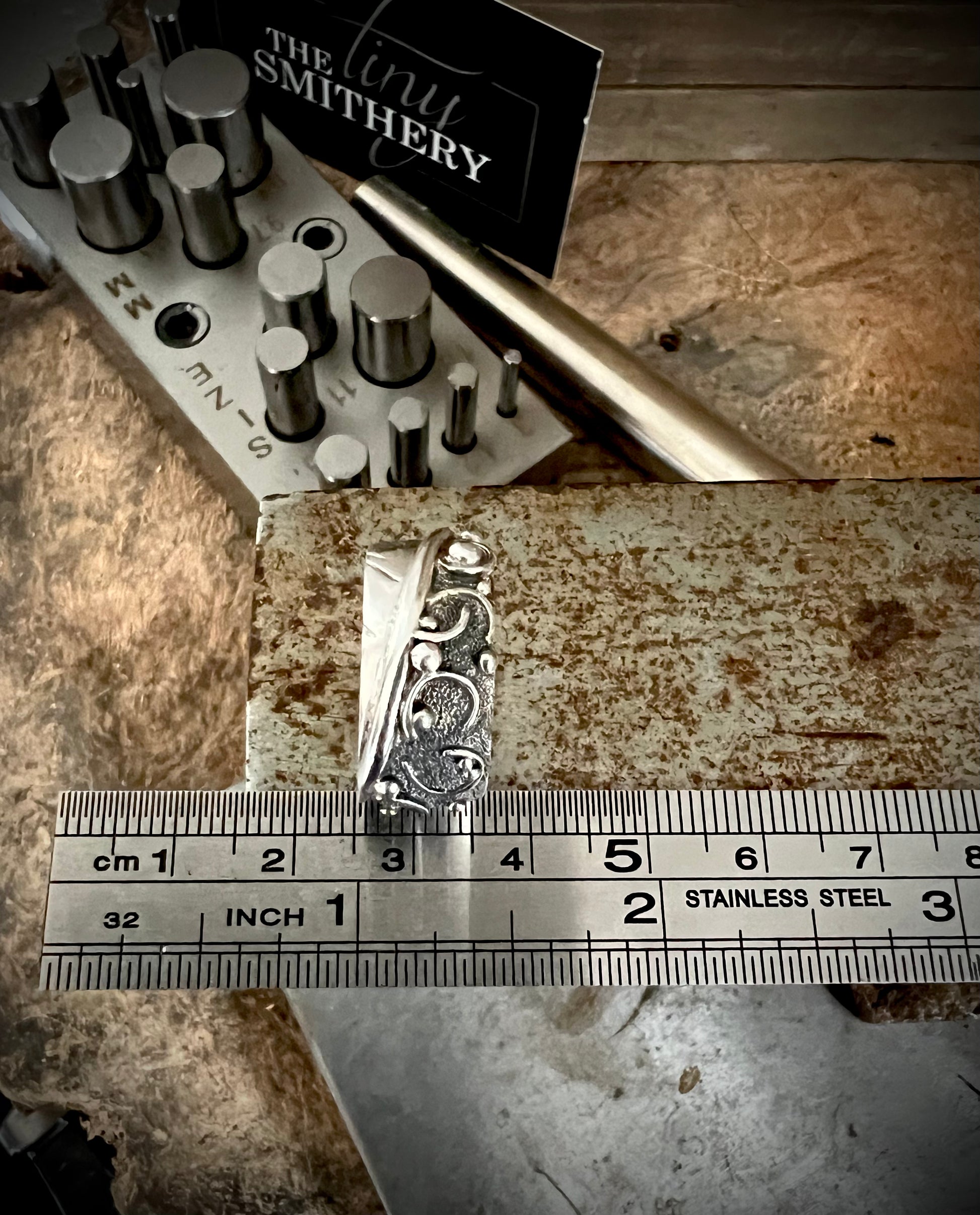 Wide Feather Ring – size reference showing sterling silver wide feather-texture band ring next to ruler, black background
