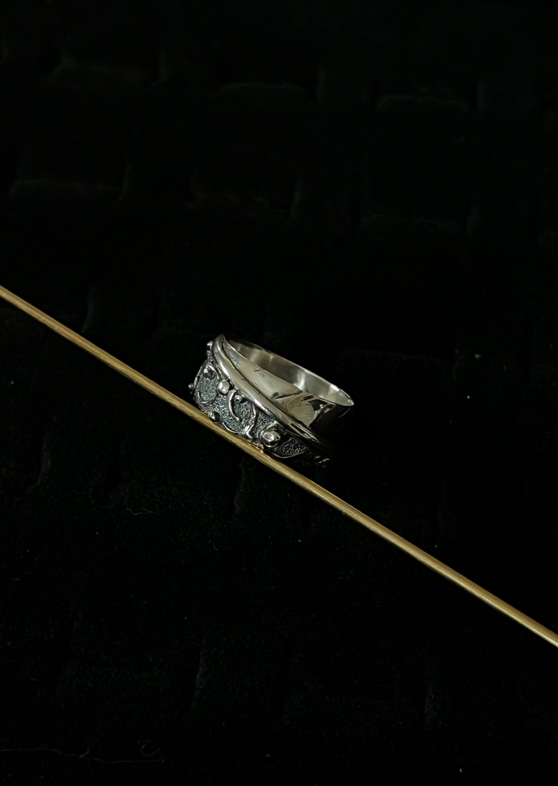 Wide Feather Ring – lifestyle shot of handcrafted sterling silver wide oxidized feather band ring worn on finger outdoors