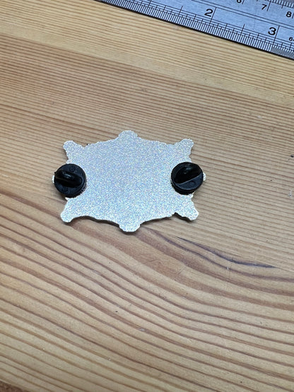 Colorado High-Grade Silver Studios enamel pin – back view showing two butterfly clasps on silver starburst pin, wooden surface