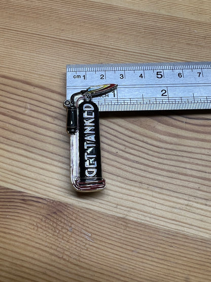 "Get Tanked" enamel pin – size reference showing pin approximately 1.5 inches tall next to ruler, wooden surface