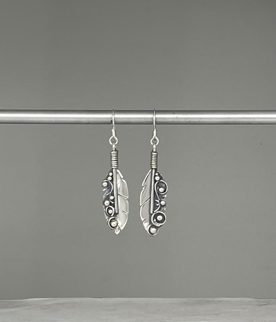 Long Feather Earrings – overhead view of handcrafted sterling silver long oxidized feather drop earrings, black background
