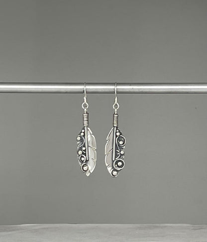 Long Feather Earrings – overhead view of handcrafted sterling silver long oxidized feather drop earrings, black background