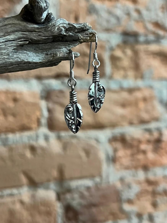 Petite Feather Earrings – close-up of sterling silver small oxidized feather drop earrings showing quill and barb texture detail, black background